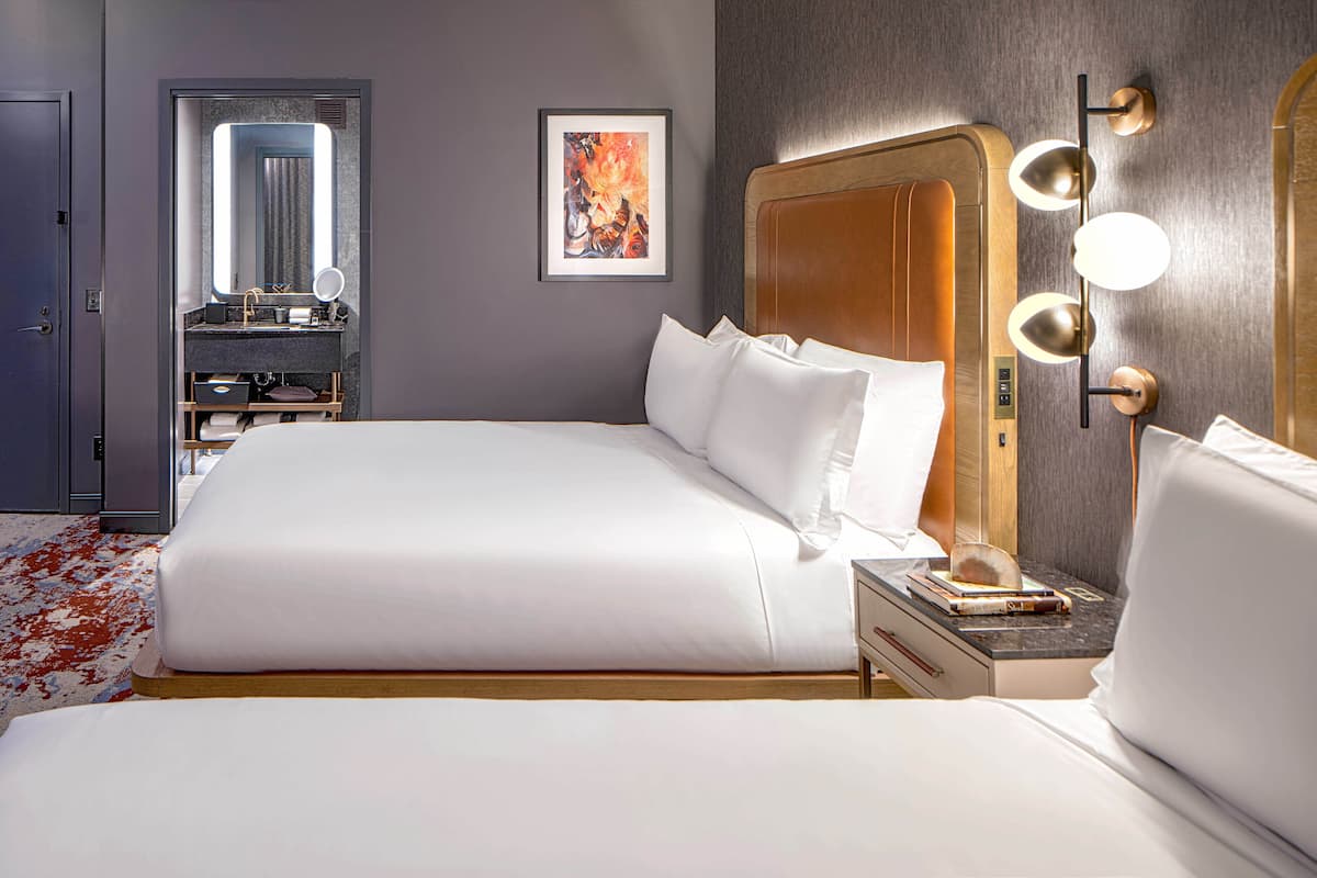 Ein modernes Hotelzimmer mit einem großen Bett, einem Schminktisch mit Spiegel und einer wandmontierten Lampe.