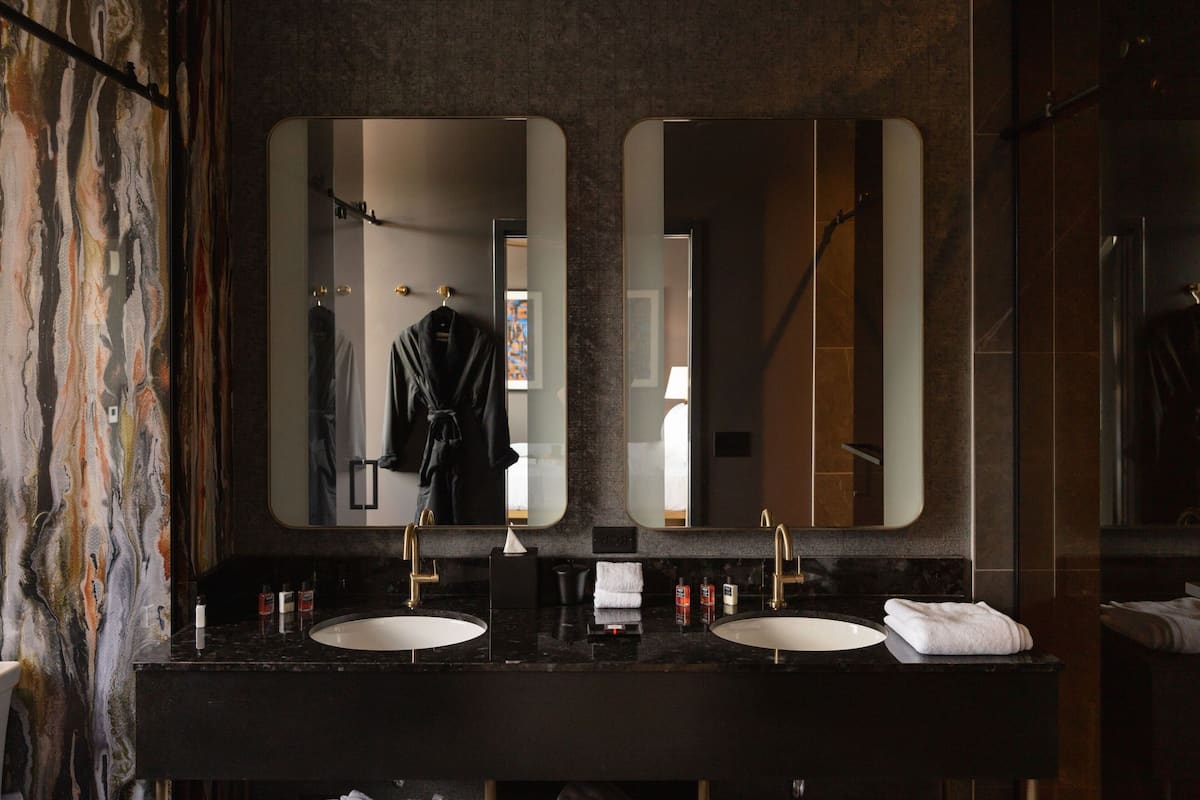 Ein Badezimmer mit zwei Waschbecken, einem großen Spiegel und einem Handtuchhalter.