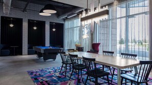 A modern room with a pool table, a large table with chairs, and large windows. - Aloft by Marriott Orlando Lake Buena Vista (Orlando)