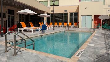 Una piscina al aire libre, sombrillas, sillones reclinables de piscina