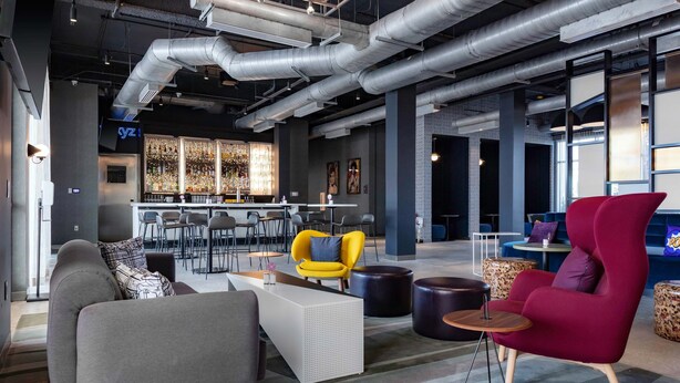 A modern lounge area with seating, a bar, and a view of the bar area. - Aloft by Marriott Orlando Lake Buena Vista (Orlando)