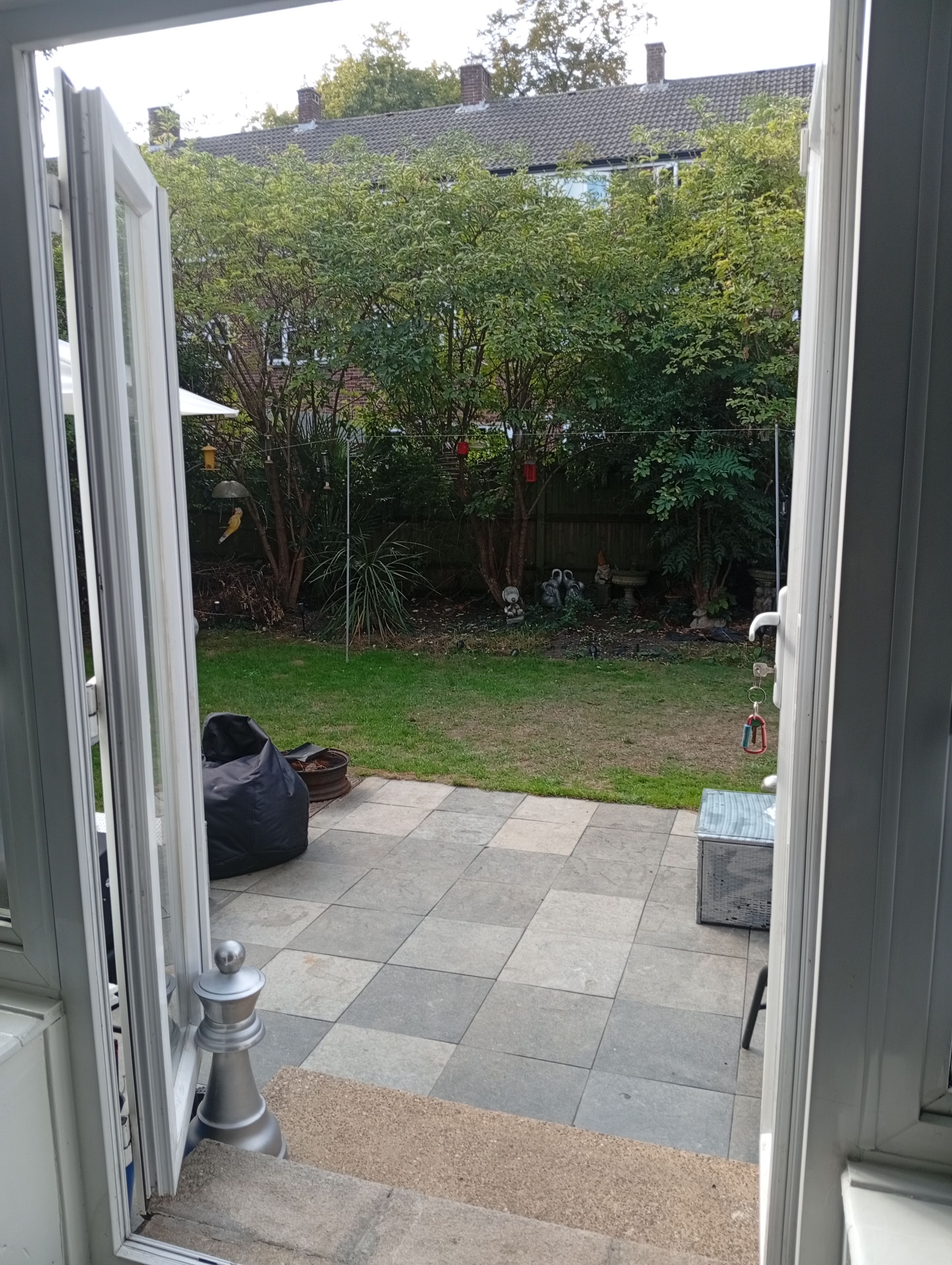 A patio area with a tiled floor, a black bean bag, and a small table.