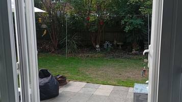 A patio area with a tiled floor, a black bean bag, and a small table.