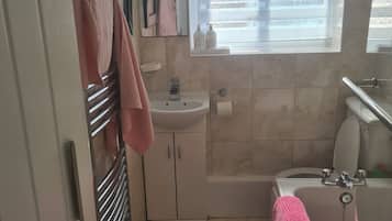 Een bad/douchecombinatie, een haardroger, handdoeken, toiletpapier