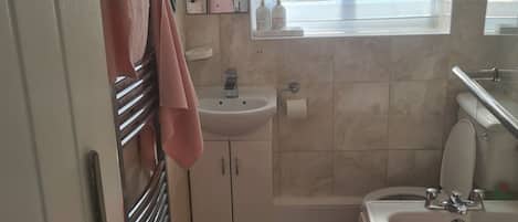 A bathroom with a sink, mirror, window, and bathtub.