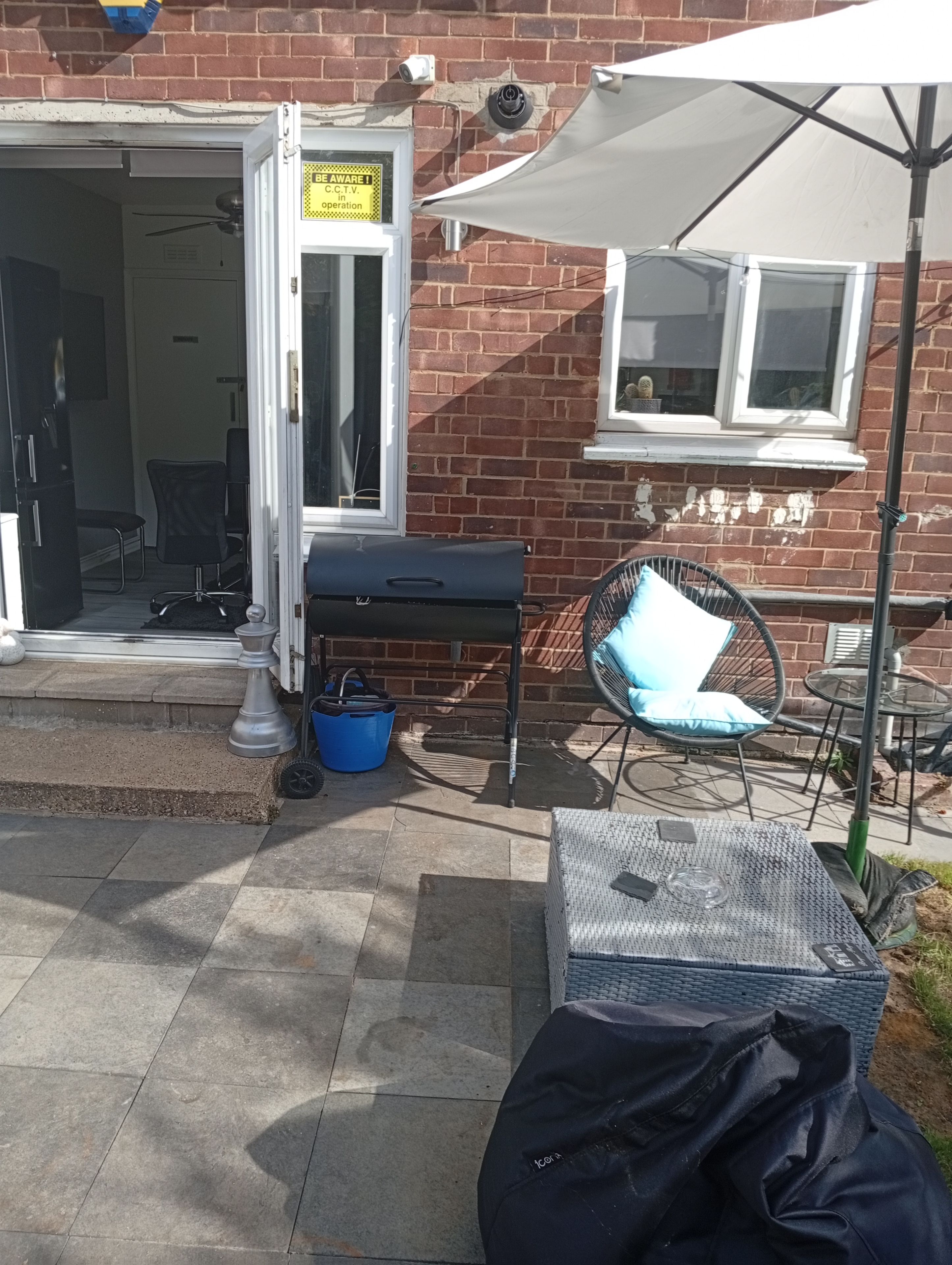 An outdoor seating area with a table, chairs, and a grill.