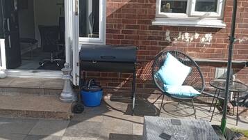 An outdoor seating area with a table, chairs, and a grill.