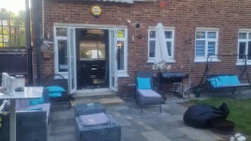 A brick building with a patio area featuring outdoor furniture and a grill.