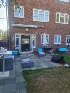 A brick building with a patio area featuring outdoor furniture and a grill.