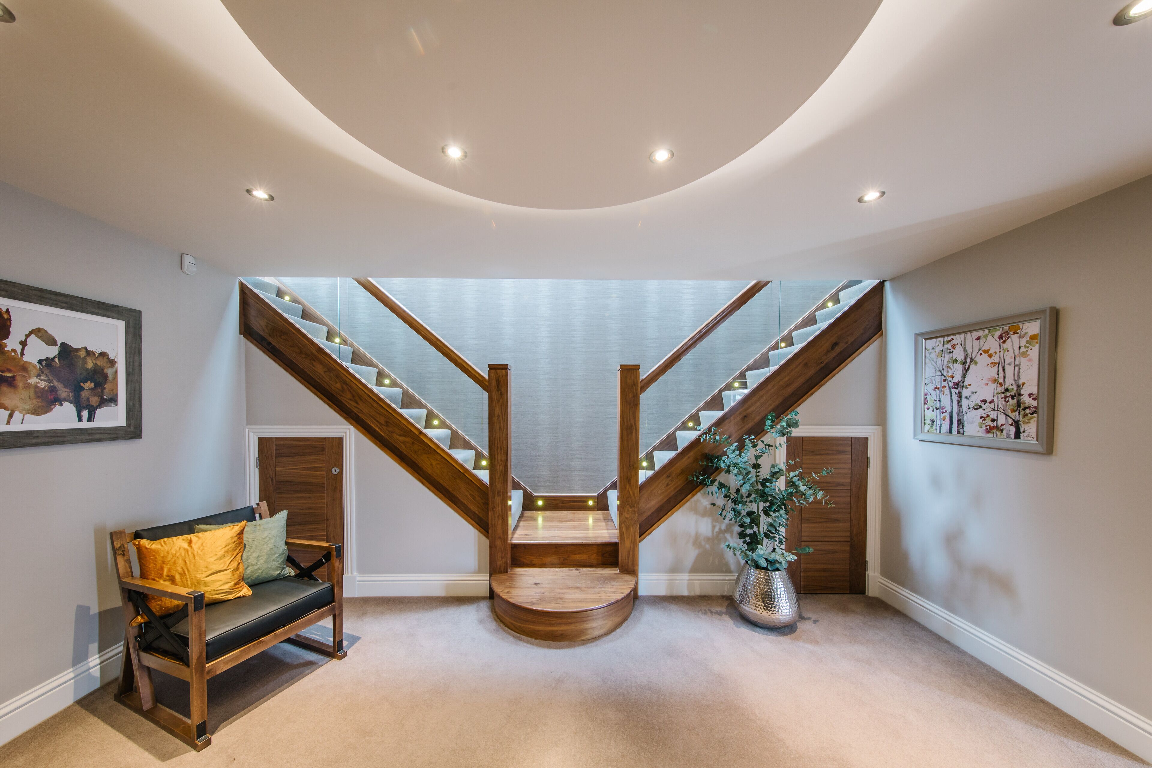 A modern interior with a wooden staircase, a bench, and framed artwork.