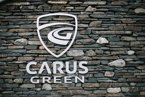 A logo with a stylized 'G' and the text 'CARUS GREEN' on a stone wall. - Carus House @ Carus Green (Kendal)