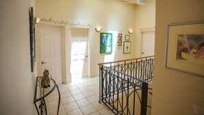 A hallway with a staircase, a door, and a wall with framed pictures. - Casa OM (Sardinal)