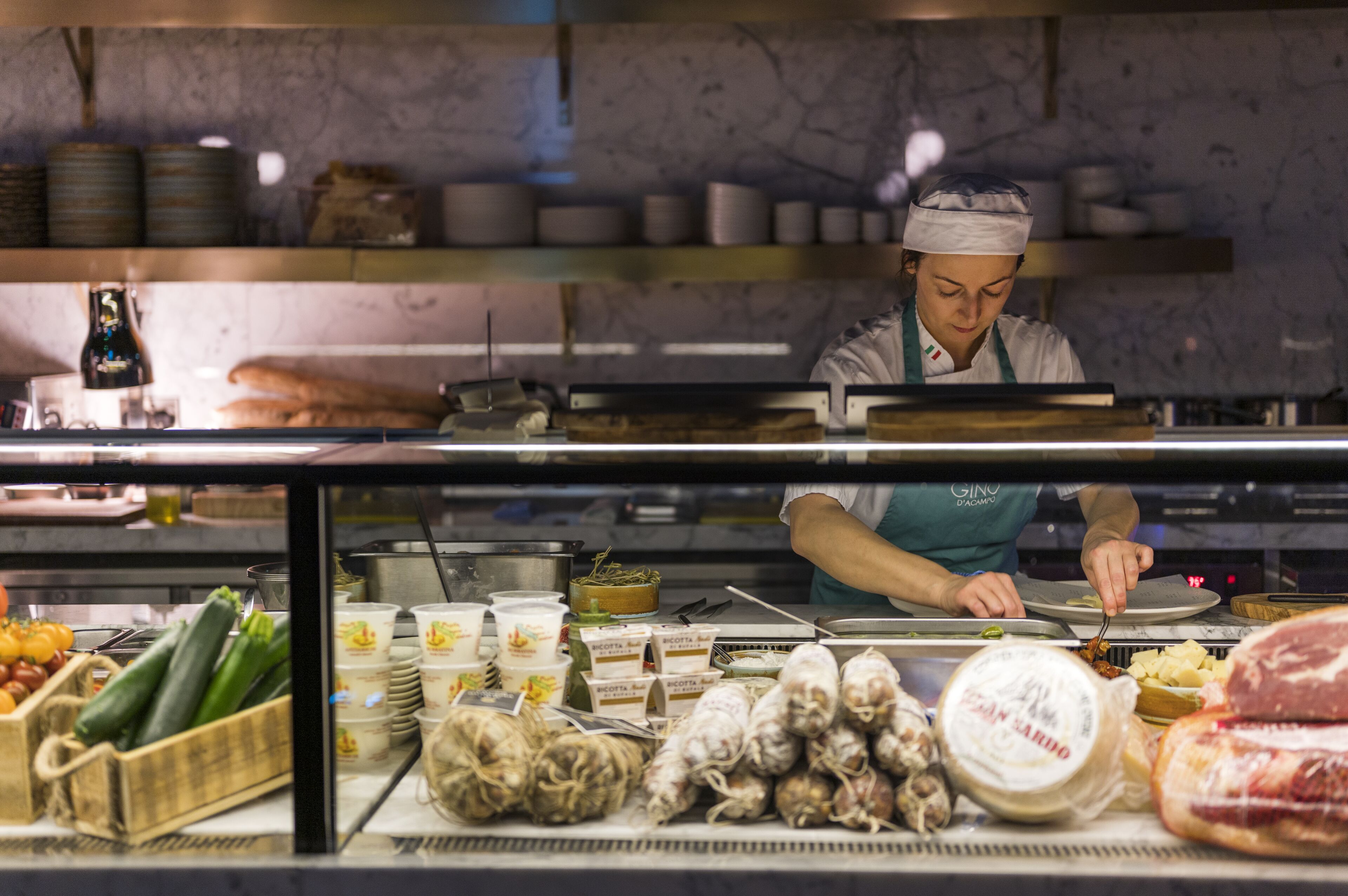 A chef preparing food in a kitchen with various ingredients and utensils visible.