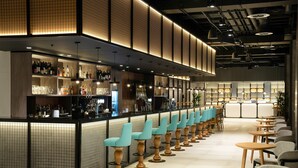 A bar area with a long counter, multiple shelves of bottles, and rows of chairs. - INNSiDE by Meliá Liverpool (Liverpool)