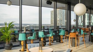 A modern indoor space with large windows, multiple seating areas, and a view of a cityscape. - INNSiDE by Meliá Liverpool (Liverpool)