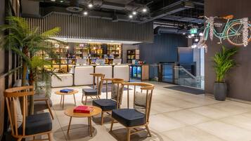 Un café moderno con sillas y mesas de madera, una zona de bar y una bicicleta decorativa.