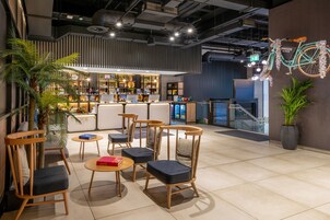 A modern cafe with wooden chairs and tables, a bar area, and a decorative bicycle.