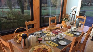 A breakfast table set with various food items, a coffee pot, and a clock. - Au Domaine du Cerf (Vyans-le-Val)