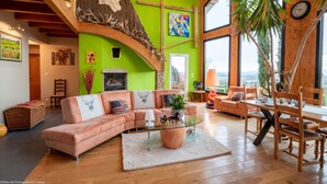 A spacious living room with a large sofa, a glass coffee table, and a dining area with wooden chairs. - Au Domaine du Cerf (Vyans-le-Val)