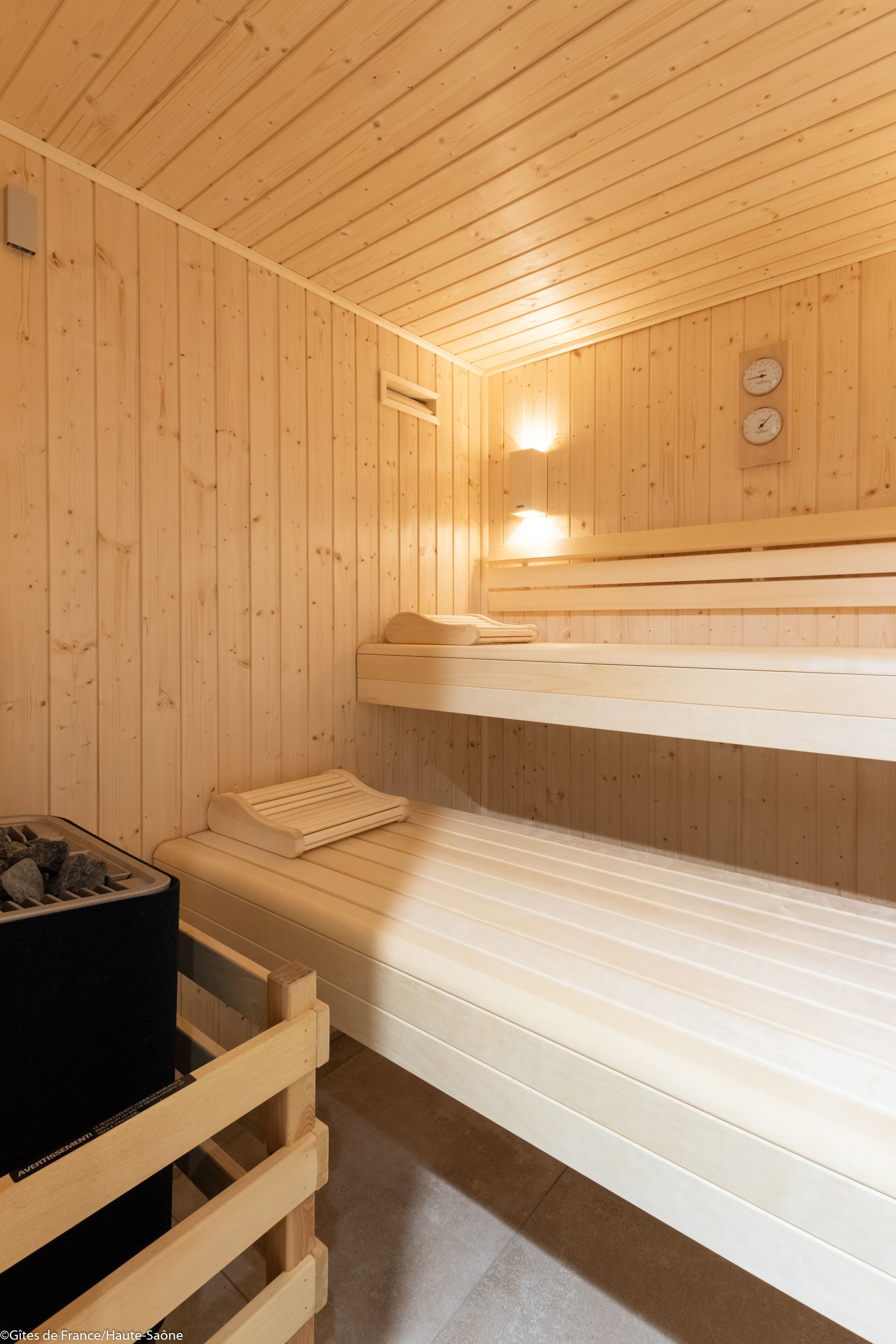 Un sauna avec des murs et des bancs en bois, un radiateur et une horloge fixée au mur.