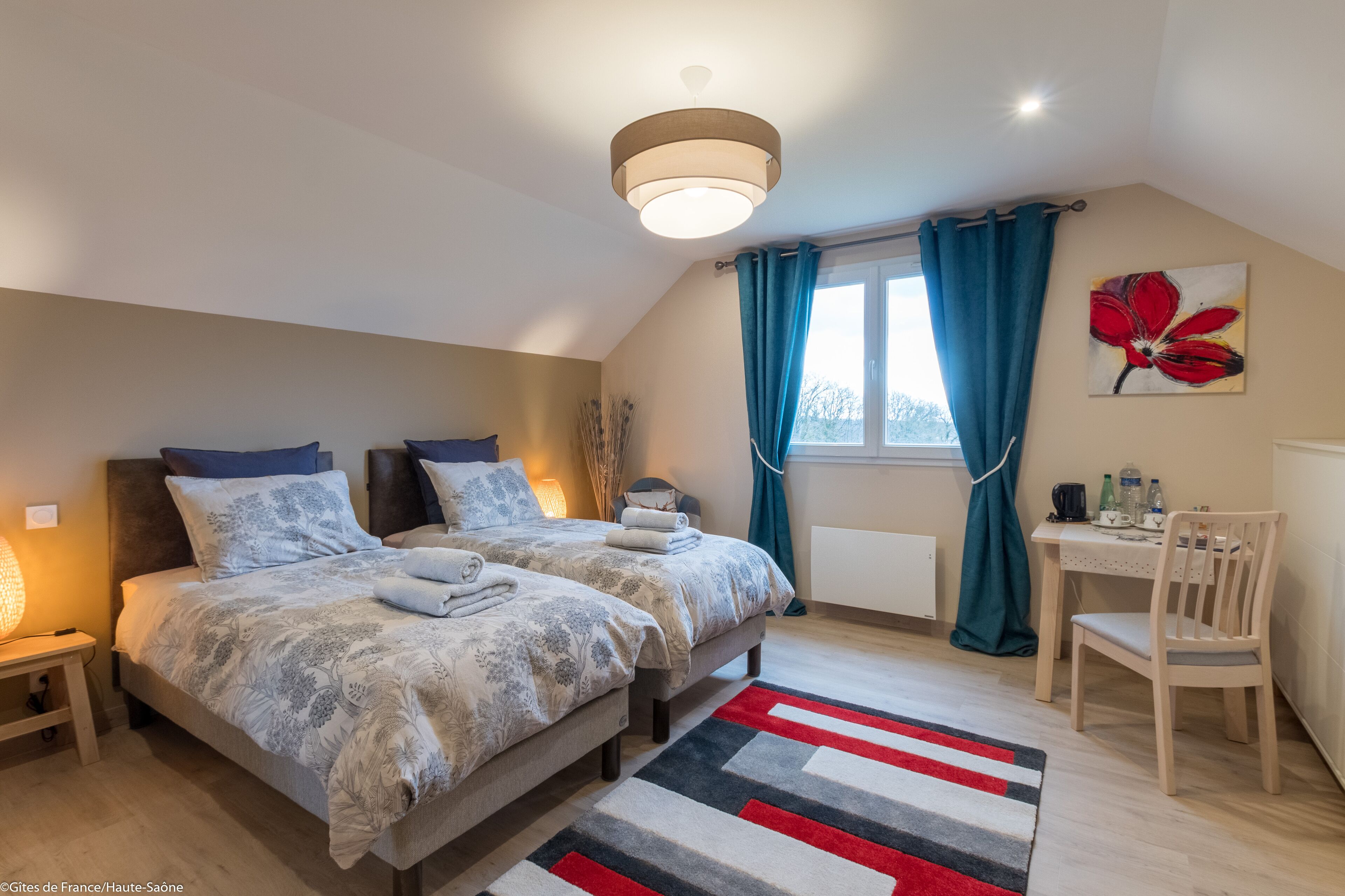 A bedroom with two beds, a desk, and a chair.