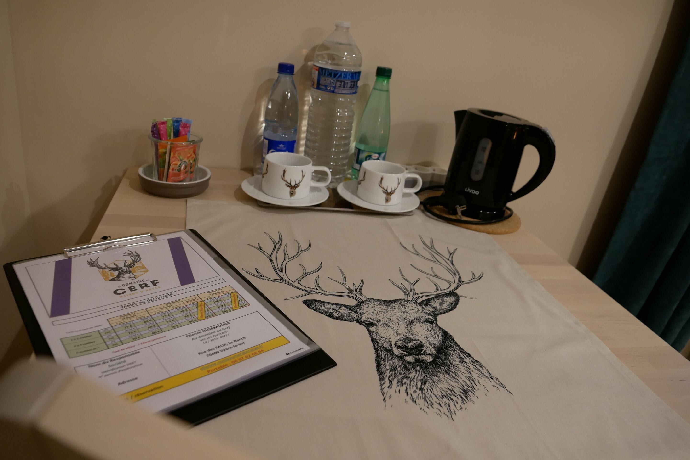 A table with a certificate, two cups, a kettle, and water bottles.