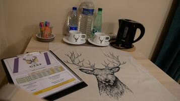 A table with a certificate, two cups, a kettle, and water bottles.