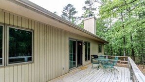 Ein Haus mit einer Holzterrasse, einer Schiebetür und einer kleinen Terrasse mit Tisch und Stühlen.