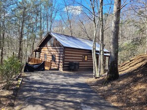 Une cabane en rondins avec un toit en métal, une véranda et un espace abrité.