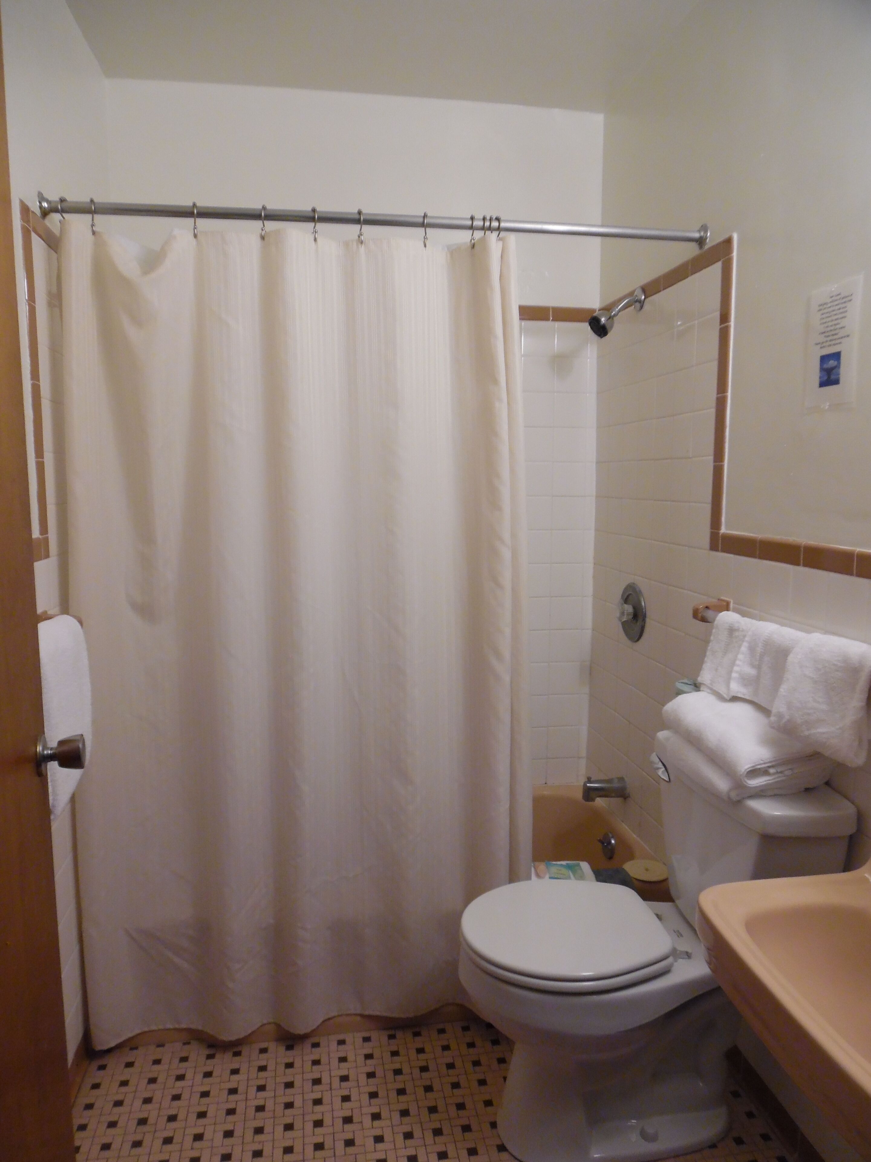 A bathroom with a shower curtain, toilet, sink, and tiled floor.