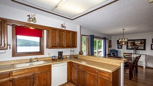 A kitchen with wooden cabinets, a large island, a dishwasher, and a window with a red valance. - 13397 - 17 Aldaya Lane (Hot Springs)
