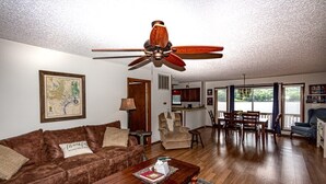 A living room with a brown leather couch, wooden coffee table, and a ceiling fan. - 13397 - 17 Aldaya Lane (Hot Springs)