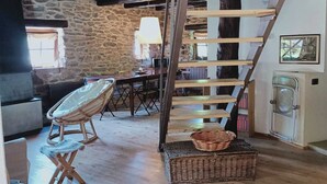 A rustic interior with a wooden staircase, stone walls, and a cozy seating area with a wicker chair and a cushioned bench. - STONE CHALET 6 pers.  ORELLE - SKI VAL THORENS + hiking/m.biking (Orelle)