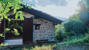 A stone house with a wooden door and window, surrounded by greenery and hills. - STONE CHALET 6 pers.  ORELLE - SKI VAL THORENS + hiking/m.biking (Orelle)