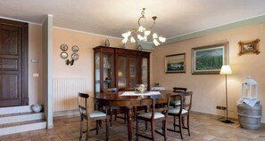 A dining room with a wooden table and chairs, a chandelier, and a cabinet.