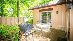Une terrasse extérieure avec un barbecue, une table et des chaises.