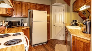 Une cuisine avec des meubles de rangement en bois, un réfrigérateur blanc, une cuisinière et un four à micro-ondes.