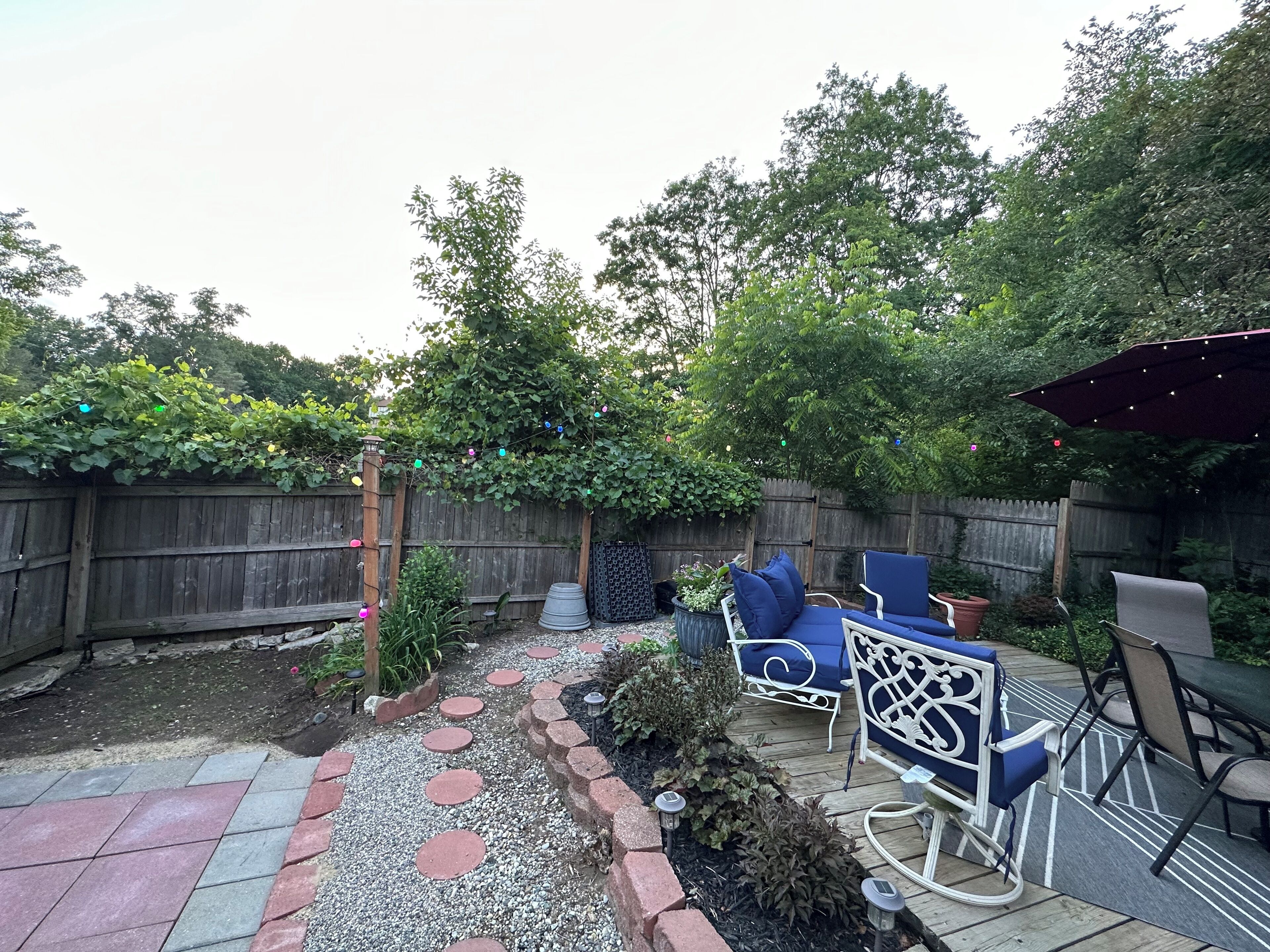 A backyard with a wooden deck, outdoor furniture, and a garden area with stepping stones.