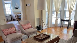 Una sala de estar con un sofá, dos sillones, una mesa de centro y un comedor con una mesa y sillas.