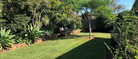 A well-maintained grassy area with a wooden bench and a variety of plants.