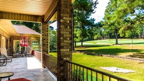 A covered patio with outdoor furniture, a stone wall, and a view of a golf course. - 18810 - 10 Cruzado Lane (Hot Springs Village)