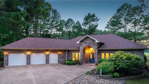 A two-story house with a brick exterior, a front porch, and two garage doors. - 18810 - 10 Cruzado Lane (Hot Springs Village)