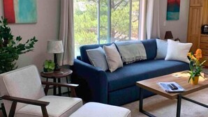 A room with a blue sofa, a white armchair, a small round table with a lamp, and a wooden coffee table. - Villa On The Boulevard, Redstone's Hidden Gem (Redstone)
