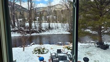 A view of a riverside patio with outdoor seating and a grill.