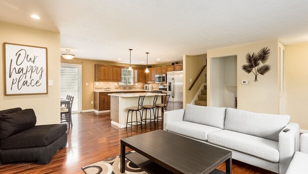 A modern kitchen with wooden cabinets, a central island, and bar stools. - COMPLETELY UPDATED 4 bedroom, 2 full bath home with deck and big yard (Columbus)