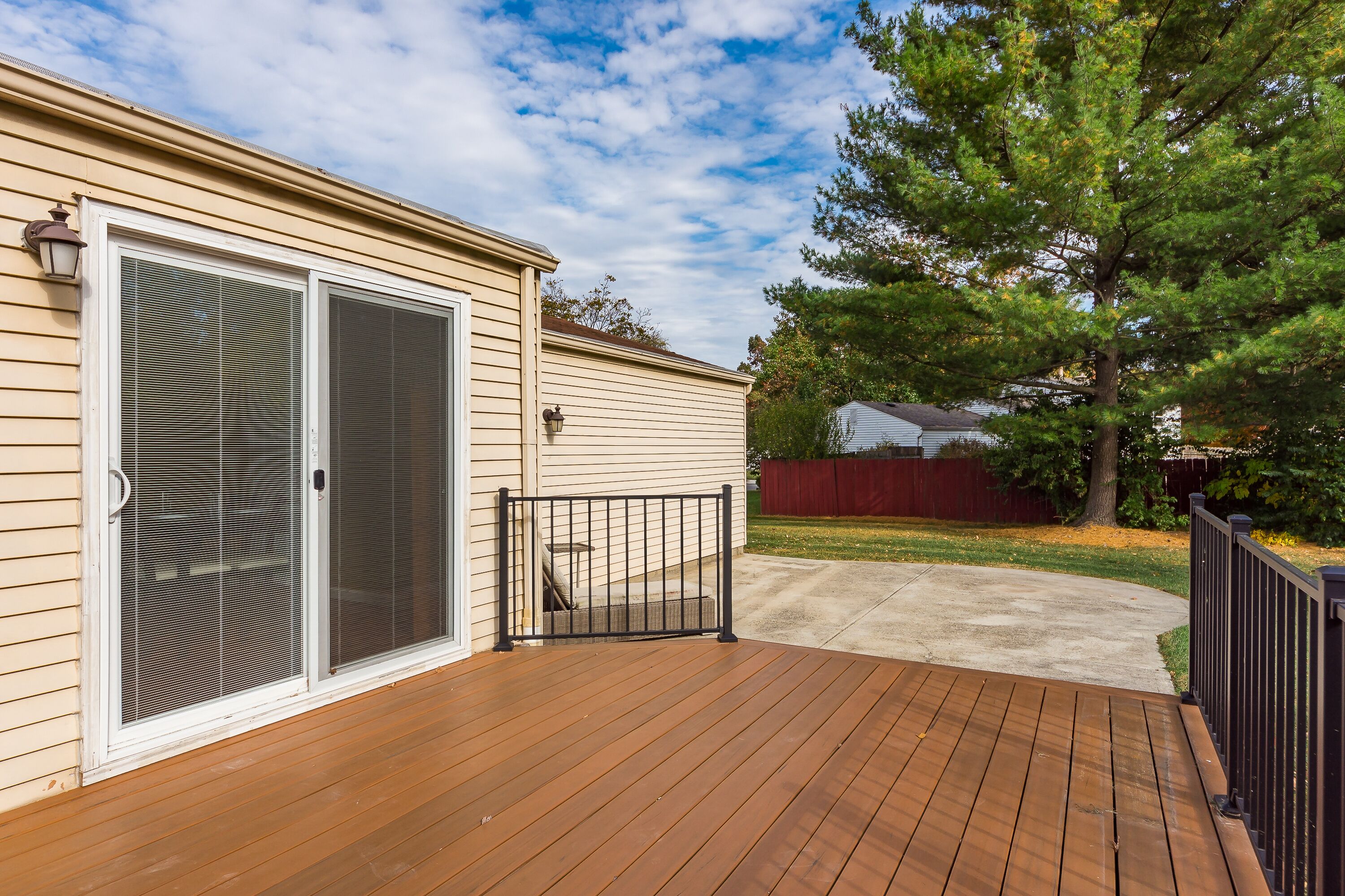 A wooden deck with a sliding glass door leading to a covered patio area.