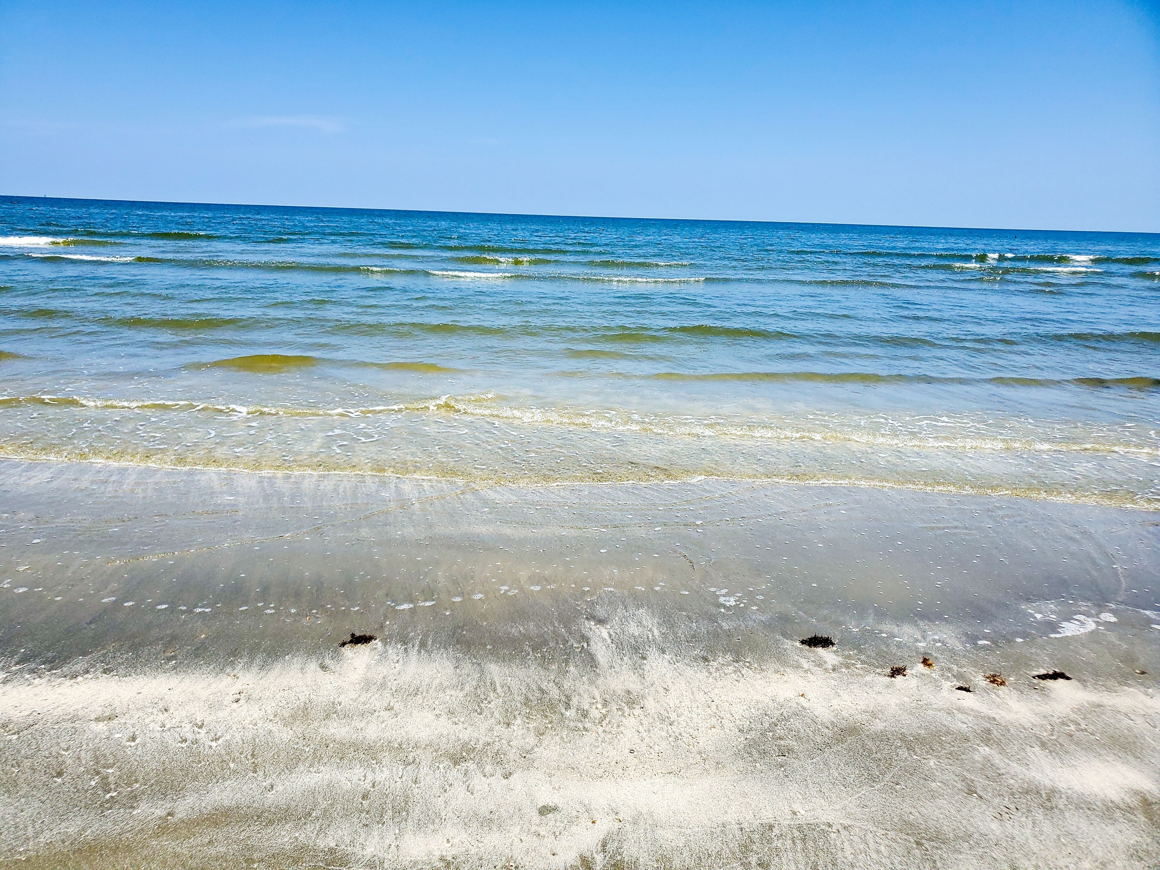 A beach with clear water and a sandy shore.