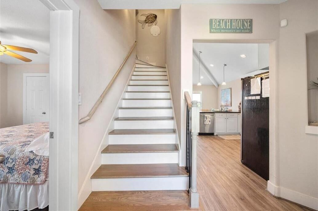 Een trap die leidt naar een keuken, met een bord waarop staat 'BEACH HOUSE'.
