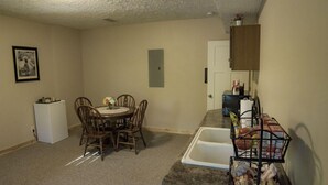 A compact kitchen with a dining table, chairs, a refrigerator, and a sink.