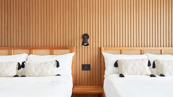 Une chambre d’hôtel avec deux lits, des murs lambrés, un petit banc en bois et un luminaire fixé au mur.